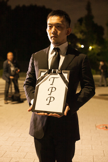 ▲喪服を着た男性。「遺影」を真似たと思われる額縁の中には「TPP」の文字