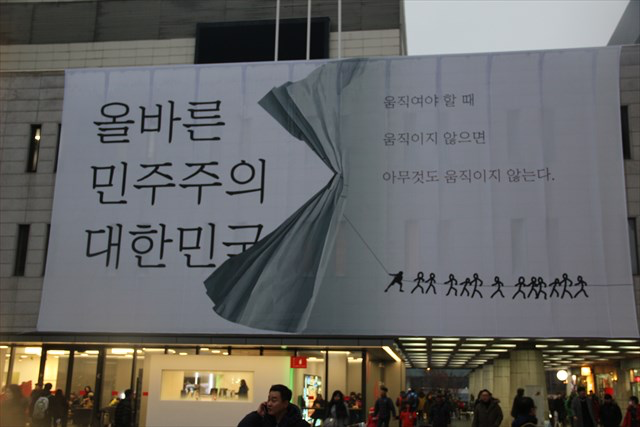 ▲光化門広場に隣接する世宗文化会館に掲げられた巨大な看板。メッセージは、左「正しい民主主義の大韓民国」右「動くべき時に、動かなければ、何事も動かない」
